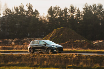 Small car on road during sunny afternoon