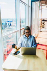 A professional woman is engaged in her work remotely, positioned in a modern office environment...