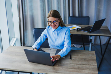 A young professional is currently engaged in remote work, showcasing a modern home office setup that is situated in a bright, minimalistic environment, which enhances focus and creativity