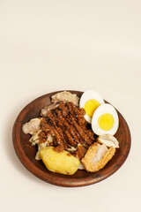 Siomay, Indonesian street food served with potato, egg, cabbage, tofu, and peanut sauce on a wooden plate. Popular savory dish in West Java.