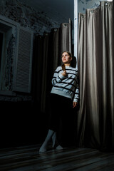 A mysterious character appears in a striped sweater within a dimly lit room featuring elegant...