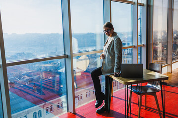 A contemplative young professional works diligently in a modern office space that offers a stunning view of the bustling city skyline, embodying ambition and a drive to succeed in her career