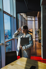 A professional businesswoman thoughtfully contemplating her future while seated near a modern...