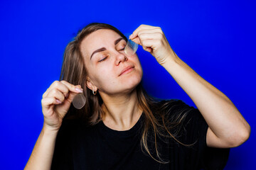 A woman skillfully applying skincare products in front of a vibrant blue background, embodying an effortless beauty routine that promotes not only aesthetics but also selfcare and wellness