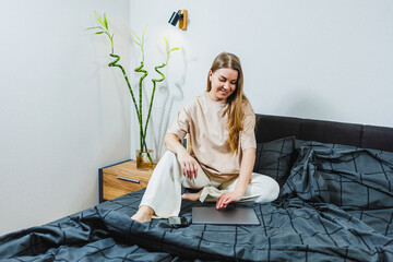 Relaxed Young Woman Sitting on Bed in a Minimalist Bedroom with Indoor Plants