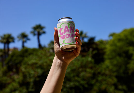 Hand Holding a Can Against a Sunny Backdrop. PSD template mockup.