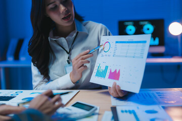 Businesswoman showing statistics chart discussing with partner in office at night