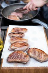 Preparing of grilled juicy fillet of duck for dinner. Chef fry meat on frying pan for main meal during barbecue. Delicious slices of meat. Food ready to eat.