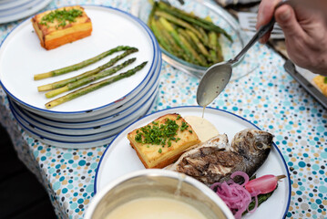 Healthy grilled fish with sauce and vegetables on a plate. Preparation a meal for lunch or dinner on barbeque. Cooking delicious food on garden party. Close up.