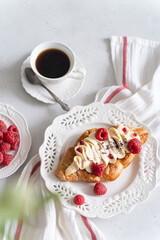 Trendy flat croissant on white plate, coffee. Delicious buttery thin croissant with fresh raspberry, cream. french breakfast. Viral Crusty flat croissant recipe, bakery, cafe menu, copy space top view