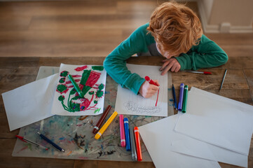 Creative child makes colorful drawing at home art station