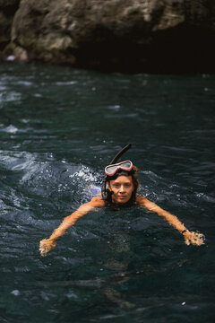 Woman snorkeling in tropical waters near rocky coastline