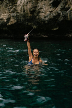 Woman snorkeling in clear tropical ocean water near rocky coastline