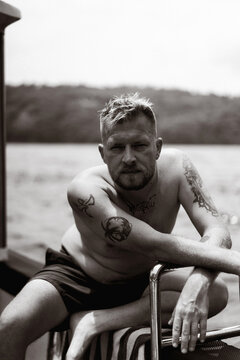 Tattooed man resting on boat in monochrome portrait, Nusa Penida