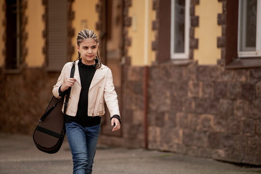 Teenage girl with violin case walking down the street