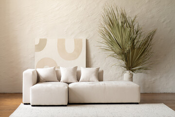 A spacious living area showcases a contemporary sectional sofa adorned with cushions, complemented by a large dried palm plant in a bright and airy setting.