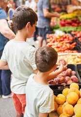 Two young boys choosing peaches at a local outdoor market