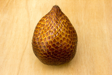 A snake fruit on a wooden board. Salak, commonly known as snake fruit, is a unique tropical fruit native to Indonesia but is now widely cultivated across Southeast Asia. 