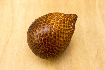 A snake fruit on a wooden board. Salak, commonly known as snake fruit, is a unique tropical fruit native to Indonesia but is now widely cultivated across Southeast Asia. 