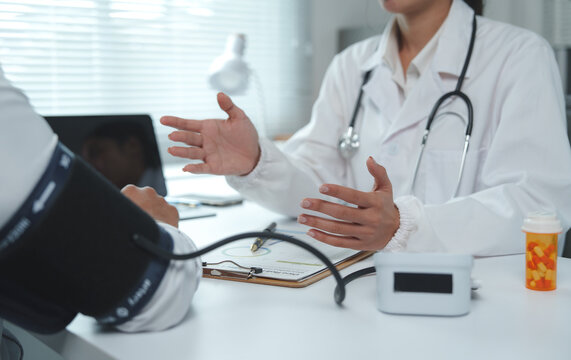 Doctor explaining diagnosis to patient during medical examination with blood pressure monitor