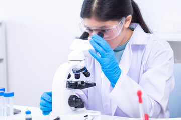 Teen girl observing a sample under the microscope during experiment. Science, laboratory,...