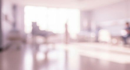 Blurred hospital room interior showing beds and chairs with bright window light.