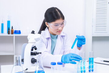 Scientist girl in lab coat observing chemical substance with care during experiment. Science,...