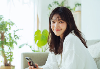 Smiling Woman Sitting at Home Using Smartphone in Bright Natural Light