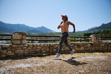 Woman Running Outdoors Against Scenic Background of Mountains and Countryside in Warm Weather