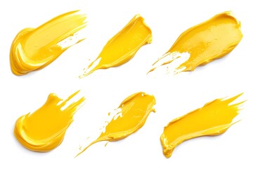 A top view of six smears of yellow paint on a white background in a studio art still life shot