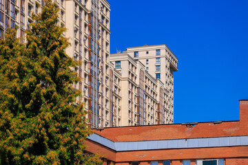 City view on a sunny day. Modern building and houses against the blue sky.
