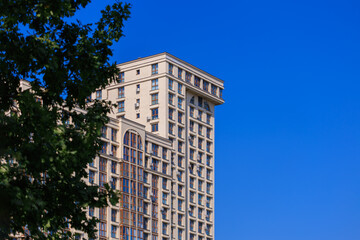 Fototapeta premium City view on a sunny day. Modern building and houses against the blue sky.