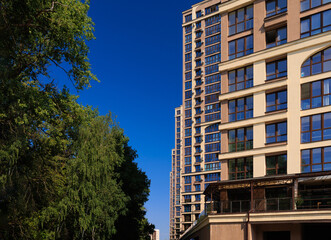City view on a sunny day. Modern building and houses against the blue sky.