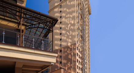 City view on a sunny day. Modern building and houses against the blue sky.