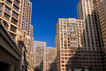 City view on a sunny day. Modern building and houses against the blue sky.