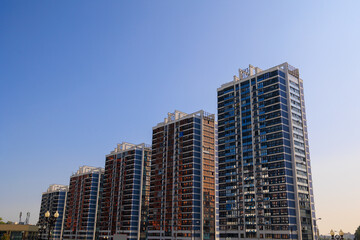City view on a sunny day. Modern building and houses against the blue sky.