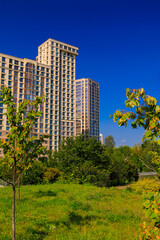 City view on a sunny day. Modern building and houses against the blue sky.