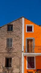 Corsica, France, Europe: a characteristic building in Corte, famous old village of the Haute Corse, with a facade divided between exposed stone and a plastered and orange painted section