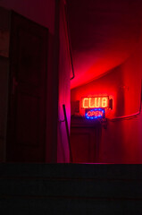 The interior of a building, entrance with the main staircase leading to the neon sign with the words Club open. Nightlife, entertainment, transgression. Symbolic, mystery, crime, thriller, spy story