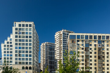 City view on a sunny day. Modern building and houses against the blue sky.