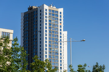 Cityscape on a summer day, modern buildings and houses against the blue sky 