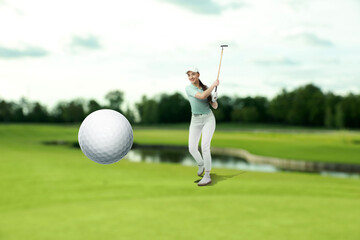 Golfer hitting ball with club on course, selective focus