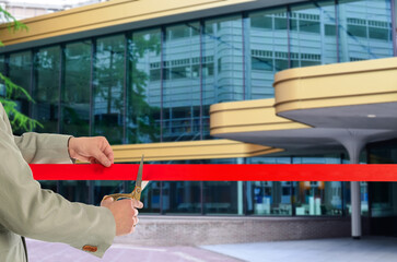 Man cutting red ribbon at opening ceremony of hotel, closeup