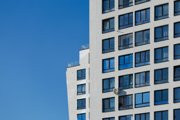 Fototapeta premium City view on a sunny day. Modern building and houses against the blue sky.
