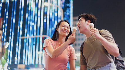 Couple enjoys ice cream together at night in Hanoi, Vietnam, surrounded by colorful lights