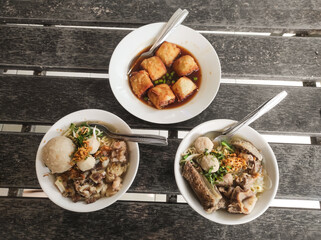 Three bowls of meat dishes. Two bowls of Indonesian meatball soup with a bowl of Gohyong spring roll complete with vinegar sauce. Indonesian specialties. Food photography. Copy space