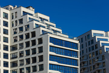 City view on a sunny day. Modern building and houses against the blue sky.