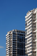City view on a sunny day. Modern building and houses against the blue sky.