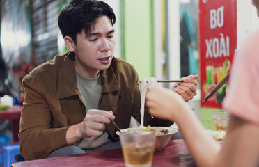Enjoying a traditional bowl of pho at a street food stall in Hanoi, Vietnam during the evening