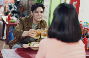 Friends enjoying drinks and food together in a lively Hanoi street cafe during evening
